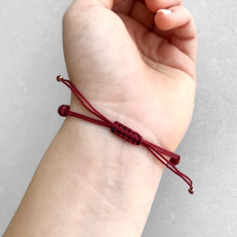 Red string bracelet with dark red beads and gold