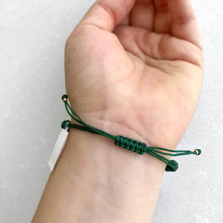 Green string bracelet with dark green beads and gold