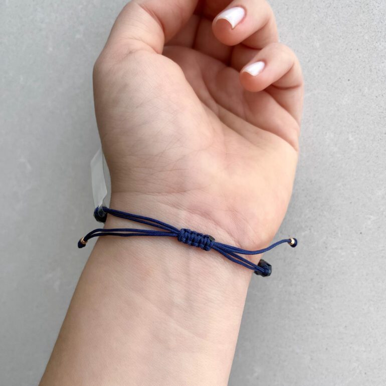 Blue string bracelet with dark blue shiny beads and gold